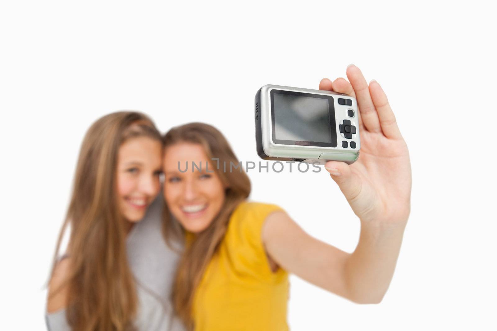 Two students taking a picture of themselves with a digital camera against white background