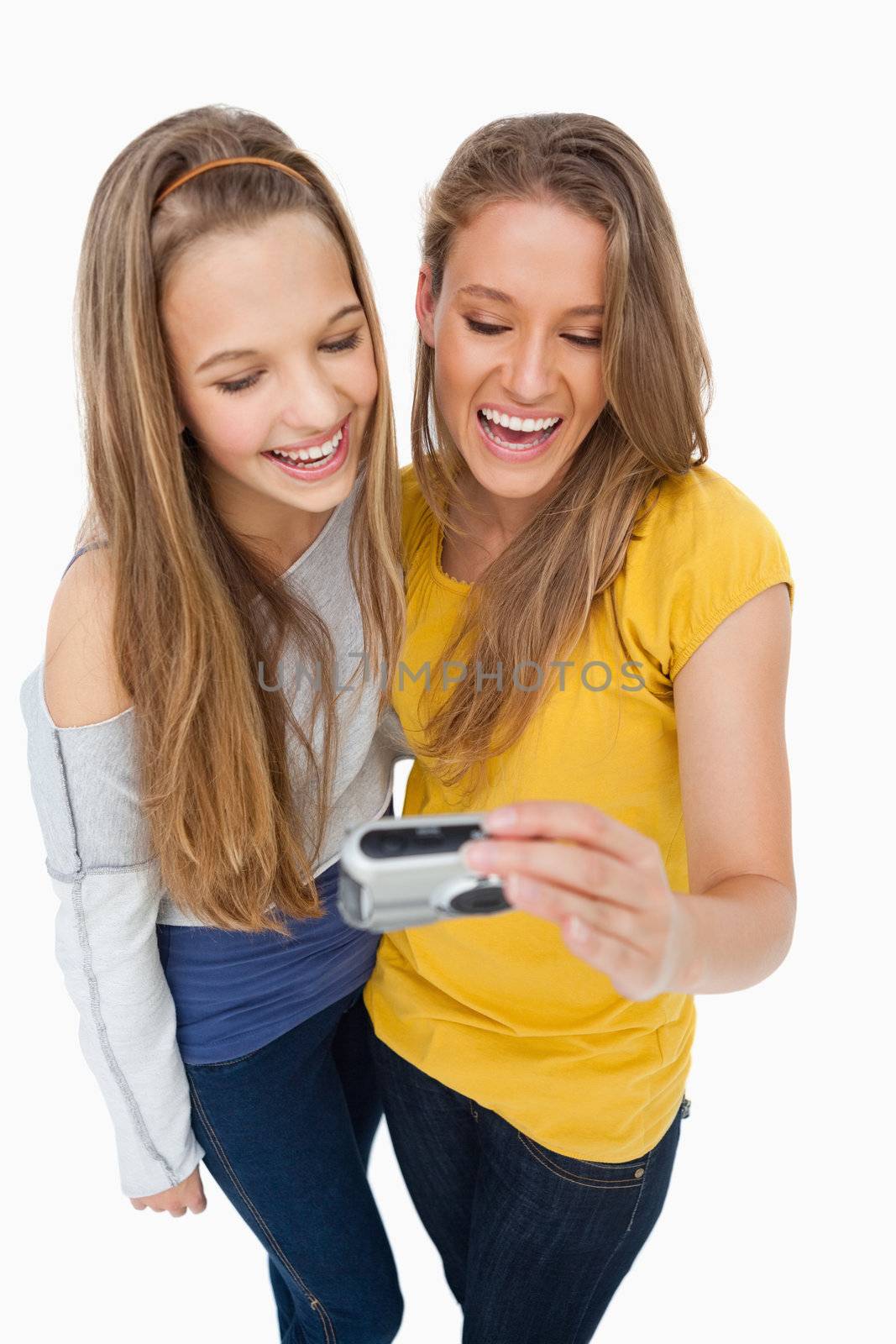 Two friends laughing while checking their picture on a digital camera against white background