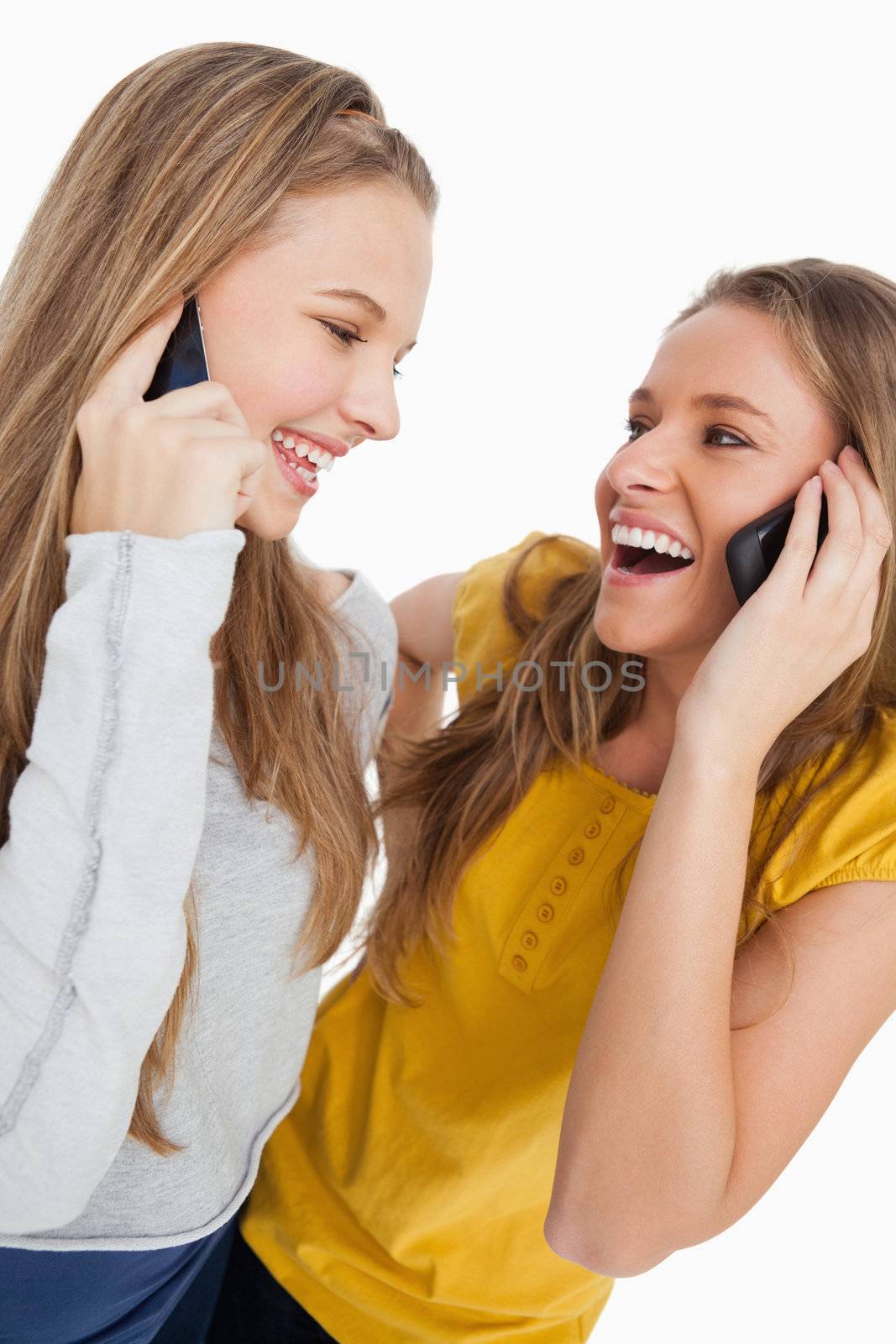 Close-up of two beautiful students laughing on the phone by Wavebreakmedia