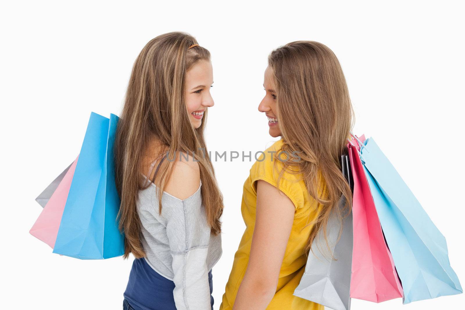 Rear view of two young women with shopping bags against white background