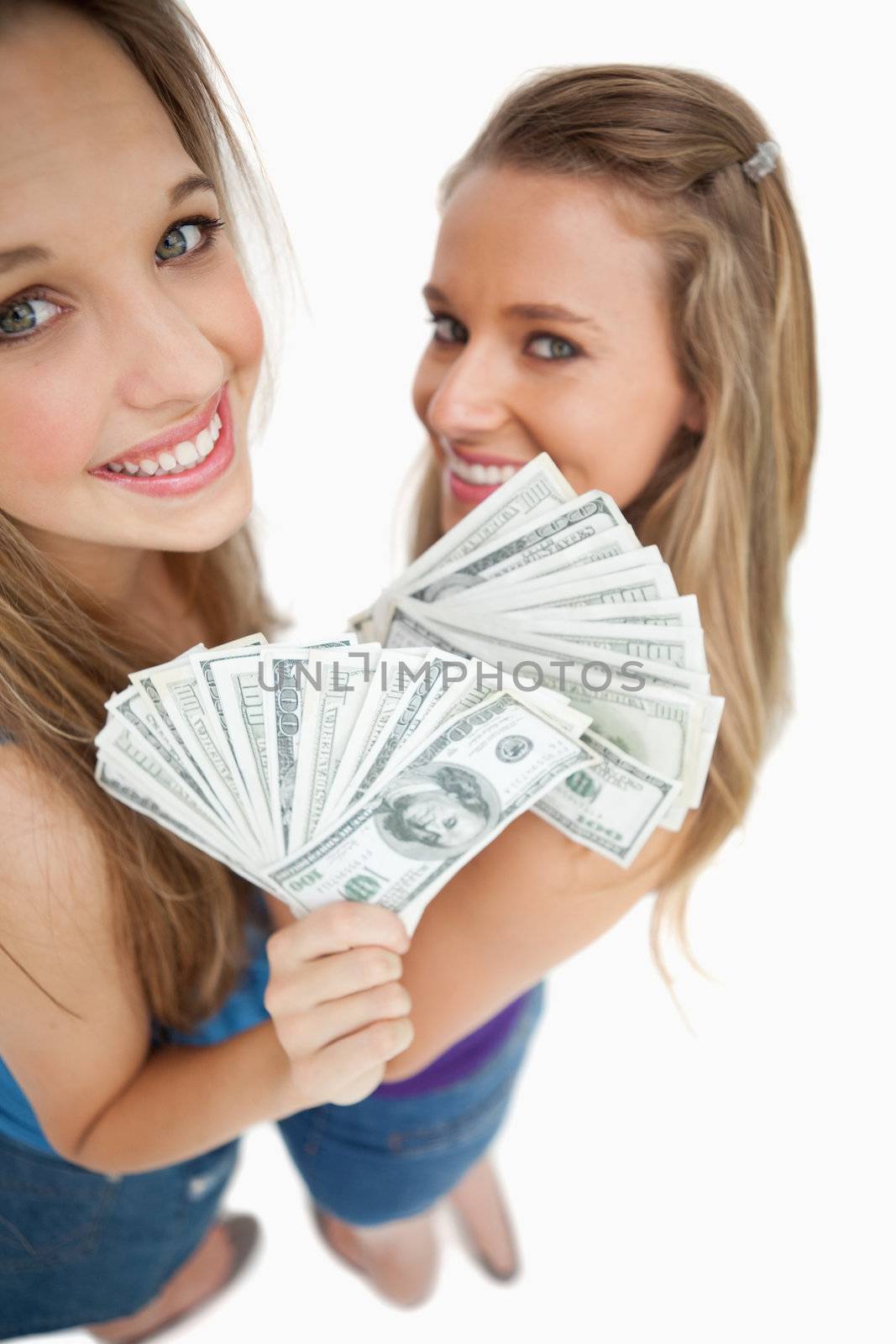 High-angle view of two young woman holding dollars by Wavebreakmedia