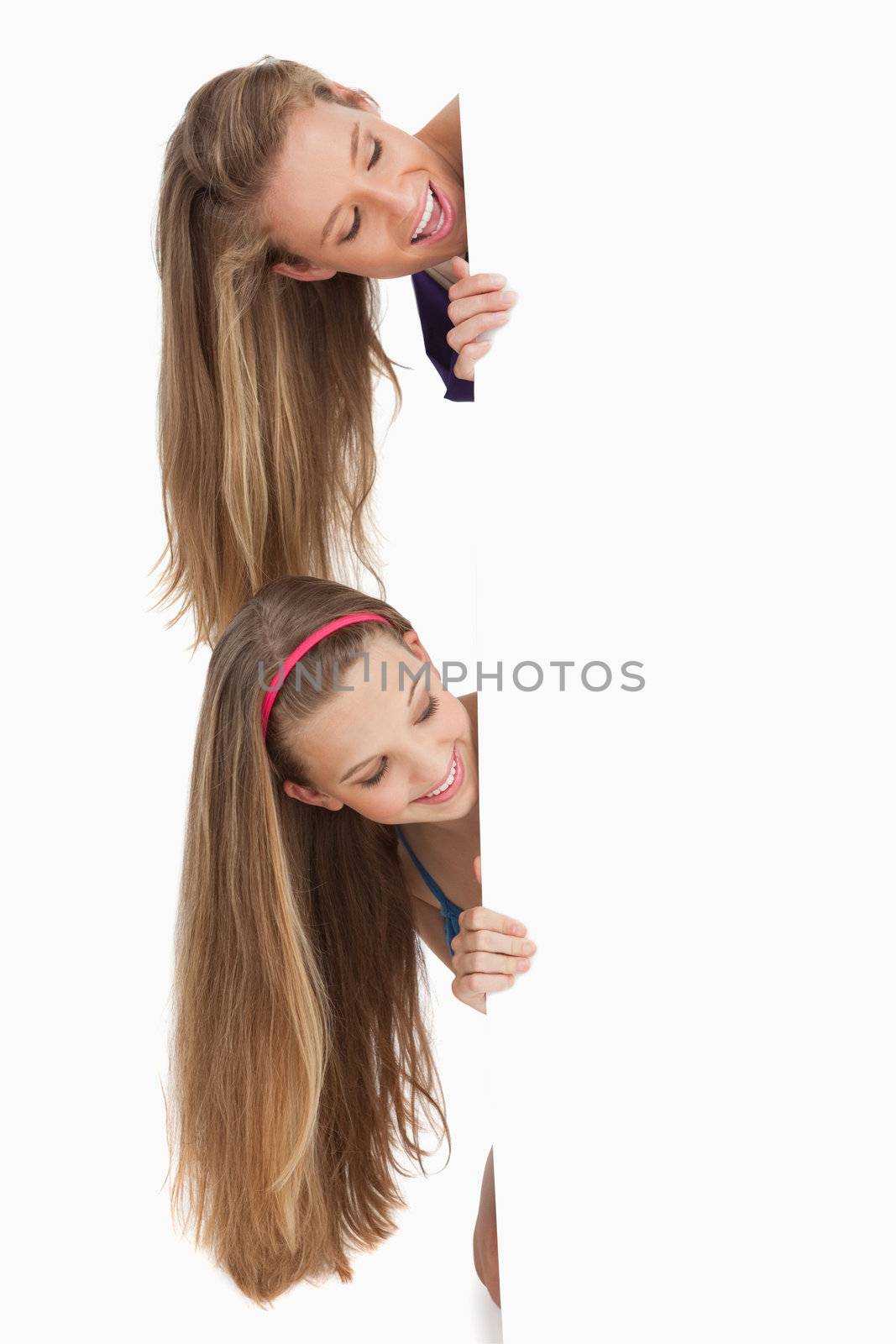 Close-up of two smiling long hair students behind a blank sign by Wavebreakmedia