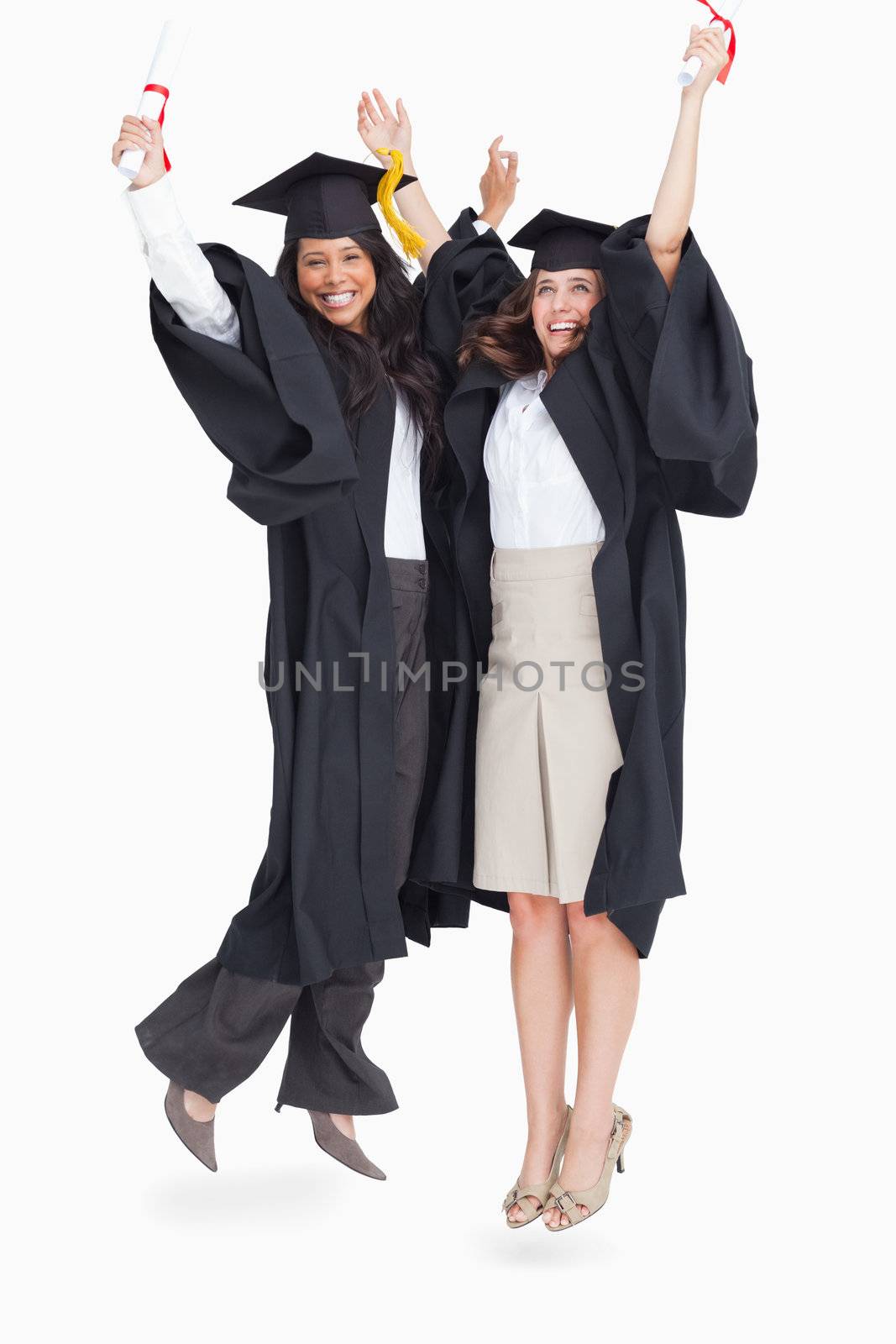 A full length shot of two women jumping in celebration after graduating 