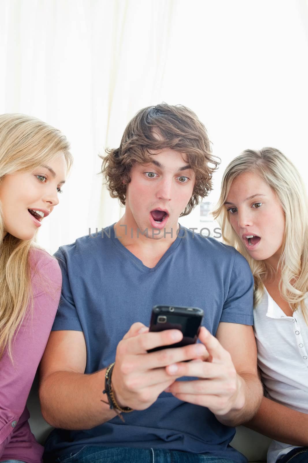 Shocked friends look at the man's phone by Wavebreakmedia