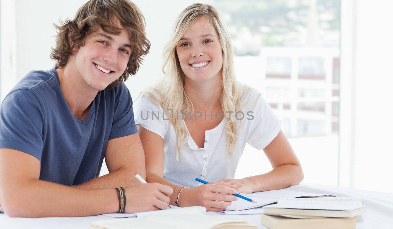 A smiling group of people sit together as they both look at the camera 