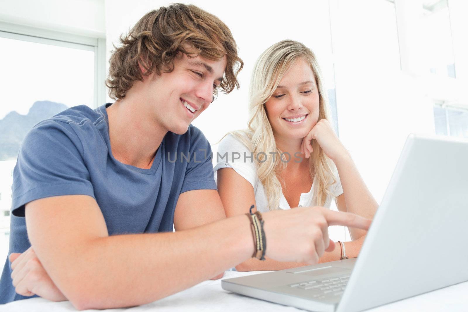 A couple sitting together smile as they look at the laptop 