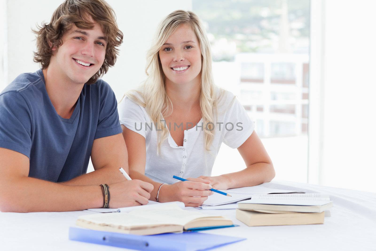 A smiling group of people sit together as they both look at the camera 