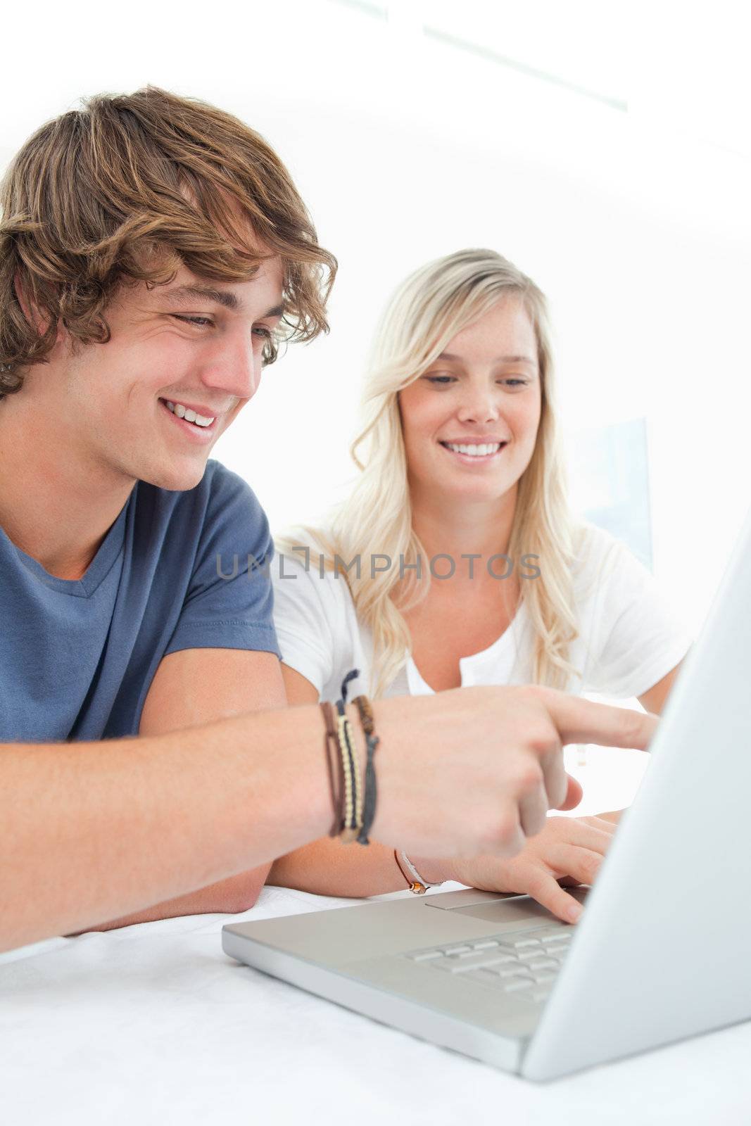 A smiling couple look at the laptop as the man points to the scr by Wavebreakmedia