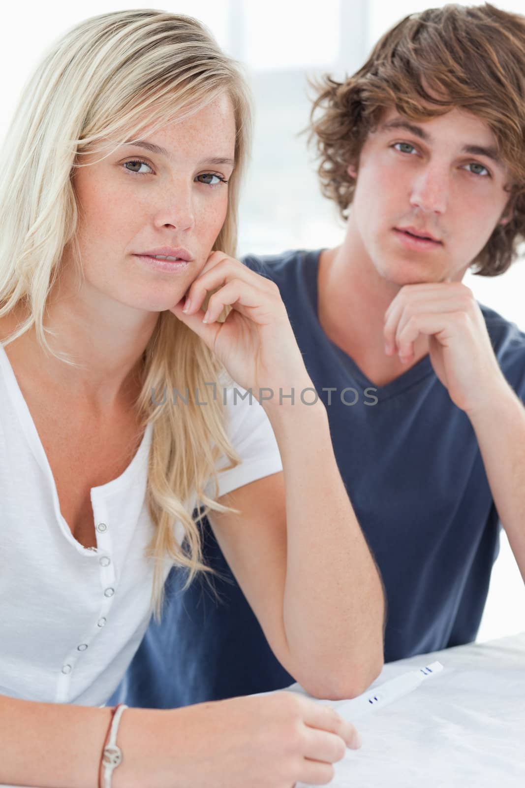 A worried couple with a pregnancy test looking at the camera by Wavebreakmedia