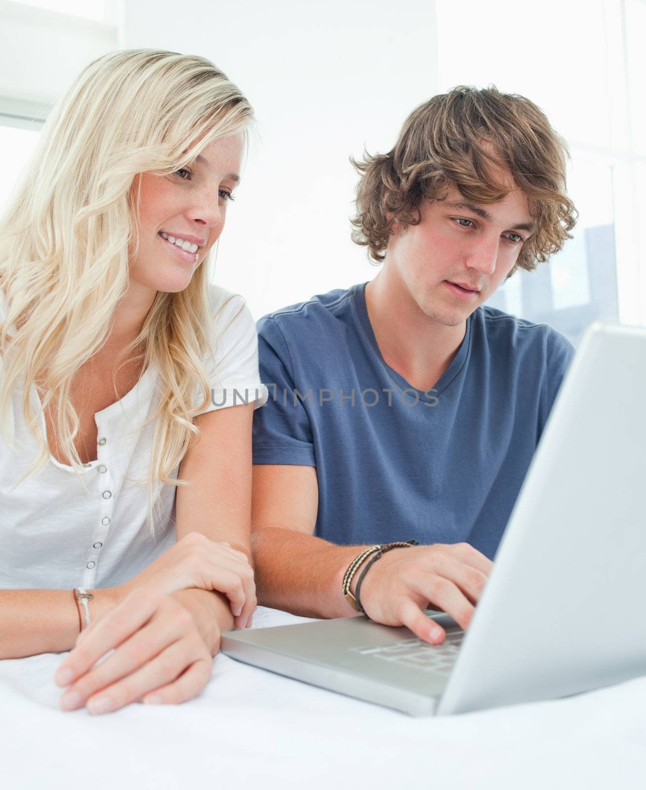 A couple using a laptop together as they sit and smile 