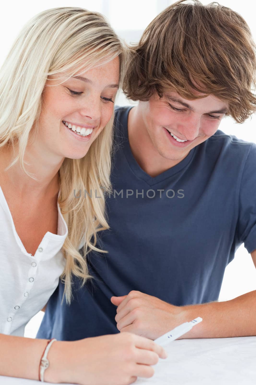 A smiling couple sitting as they look at the result of a pregnancy test 