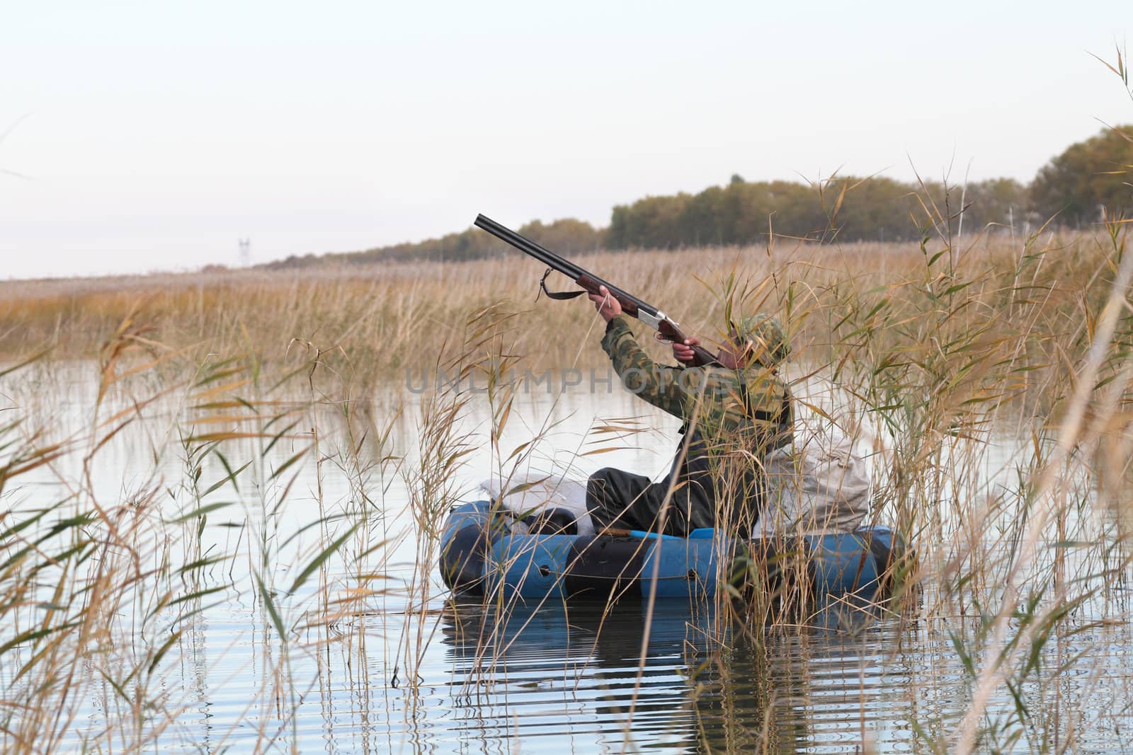 Hunter in an inflatable boat shoots duck