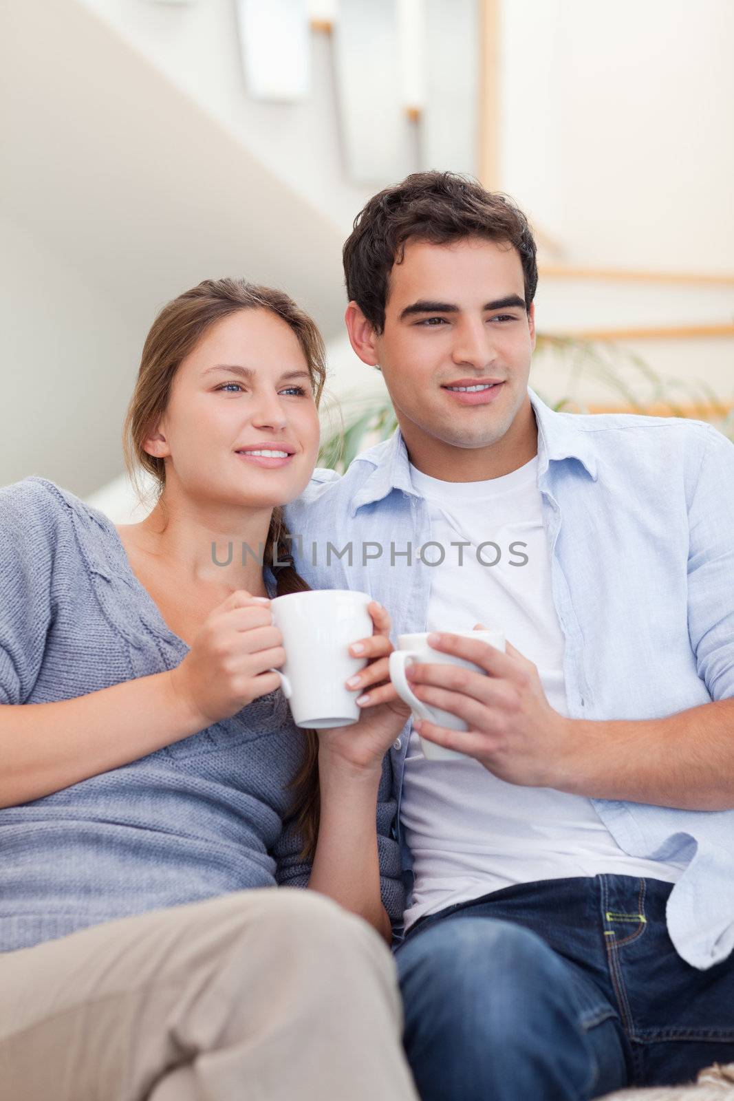 Portrait of a couple drinking coffee while watching TV by Wavebreakmedia
