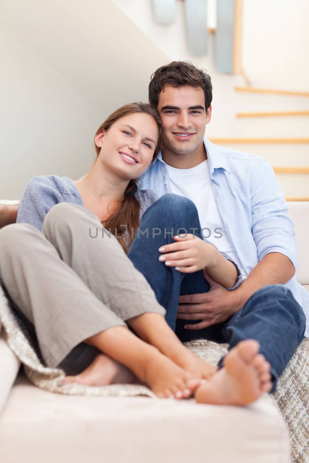 Portrait of a couple lying on a sofa while looking at the camera