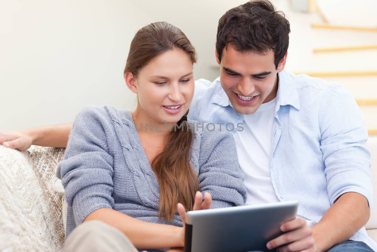 Happy couple using a tablet computer in their living room