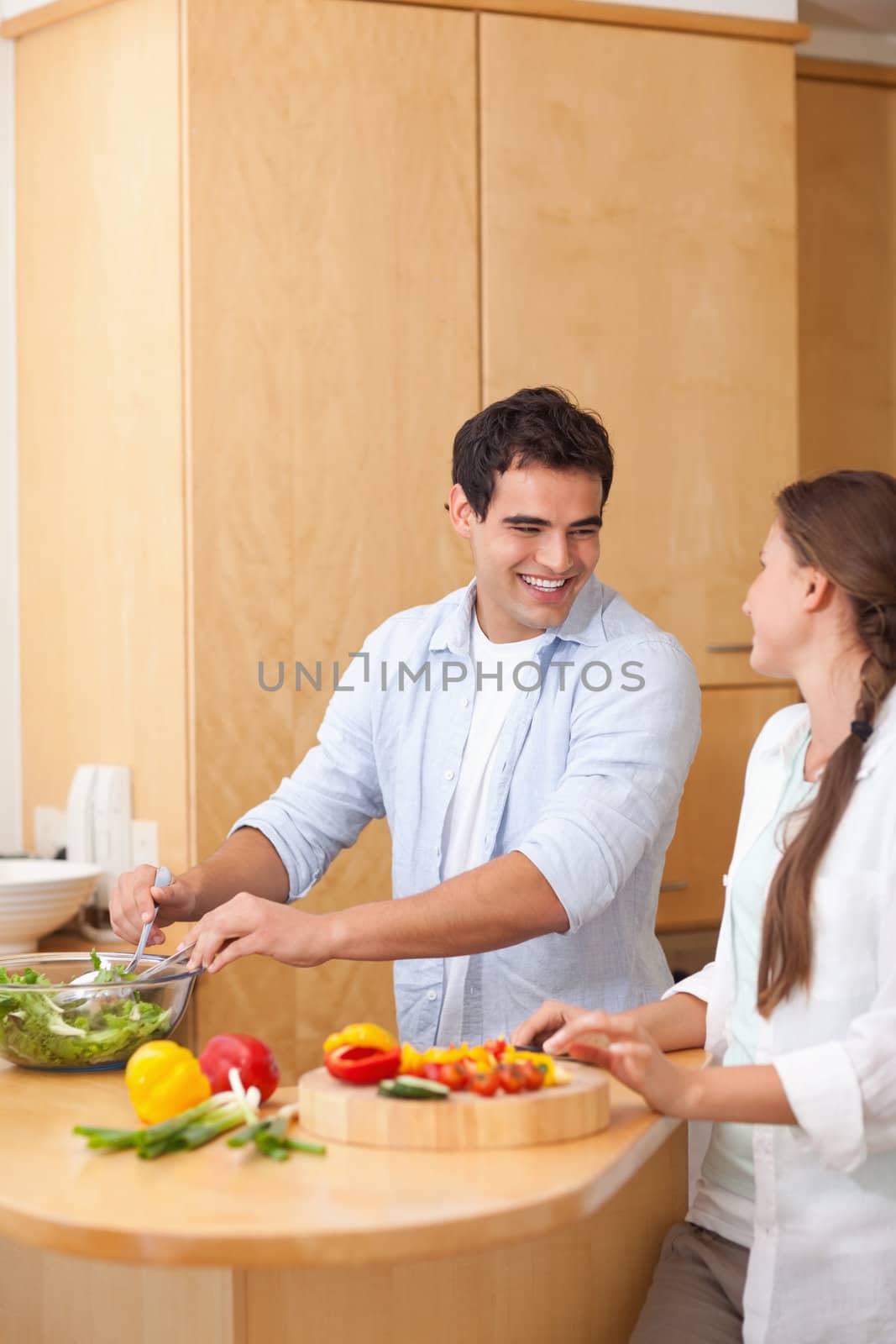 Portrait of a couple preparing a salad in their kitchen