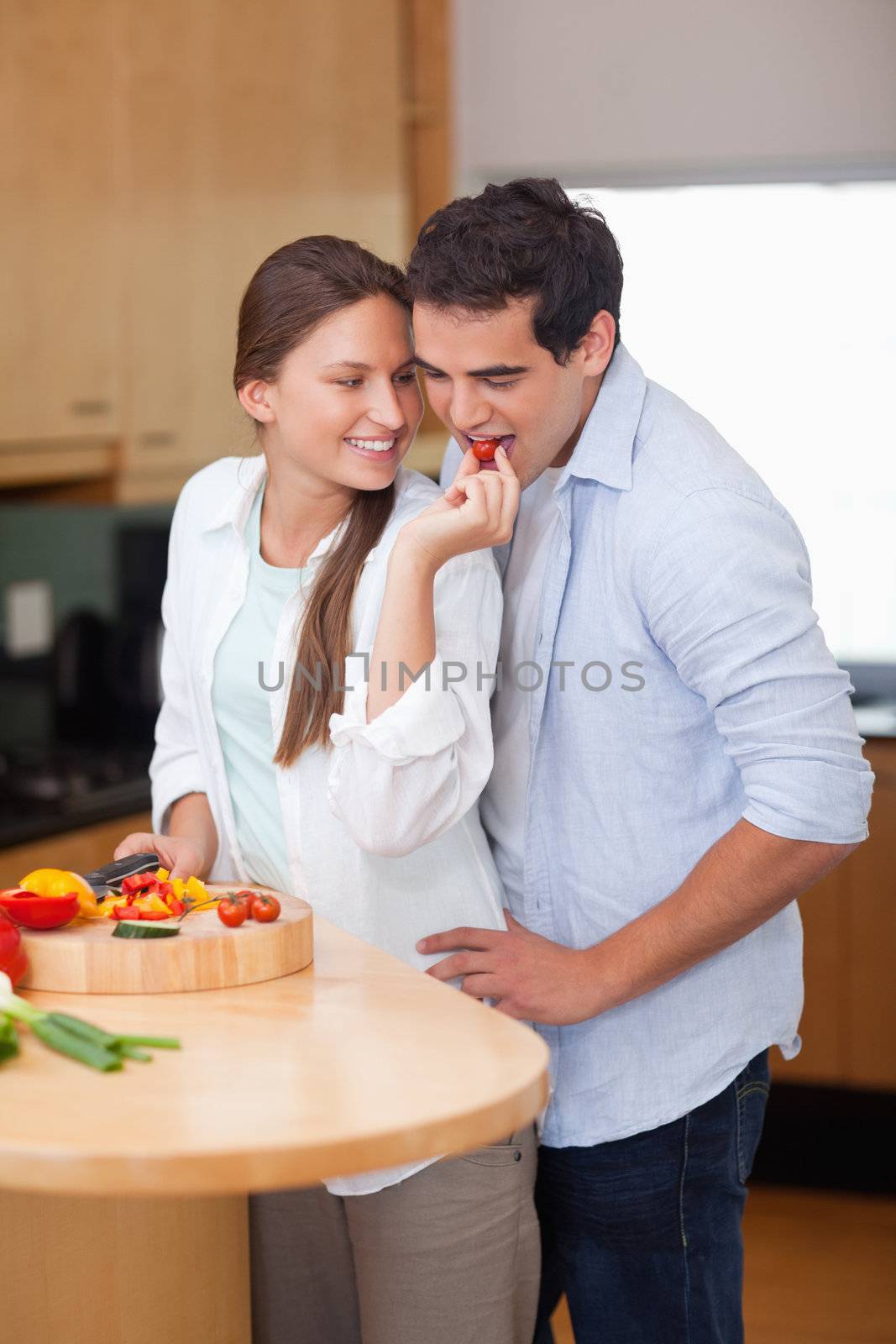 Portrait of a woman feeding her husband in their kitchen