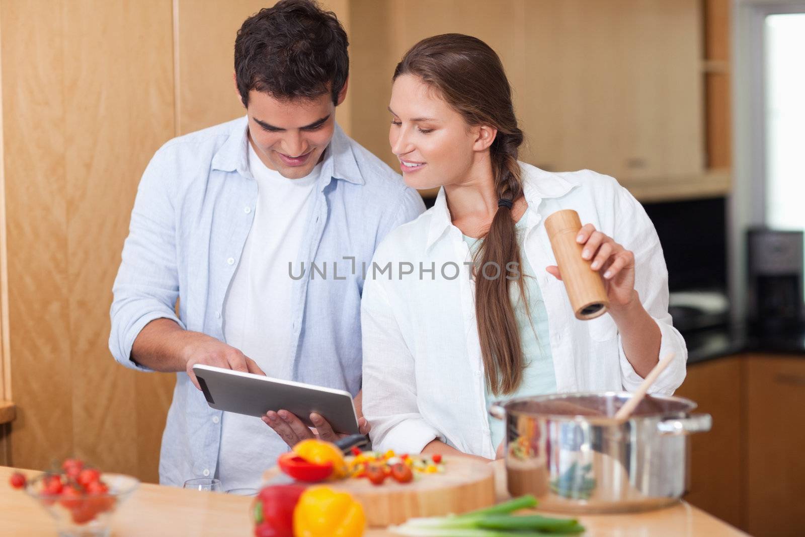 In love couple using a tablet computer to cook in their kitchen