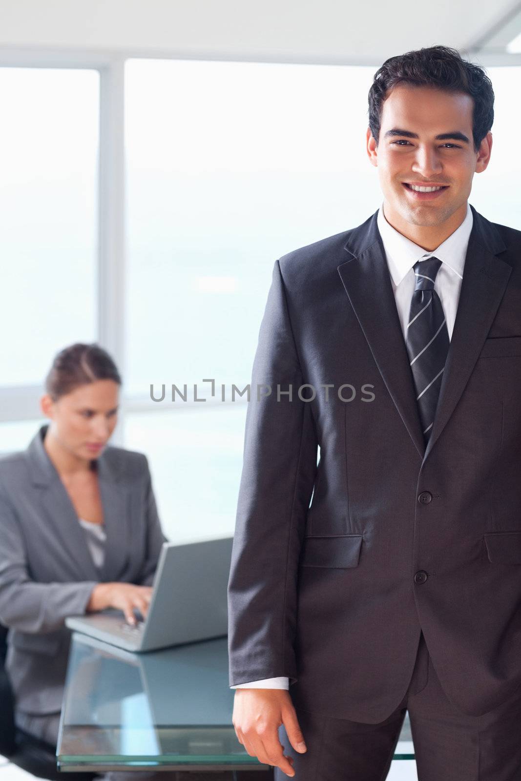 Smiling young tradesman with working colleague behind him