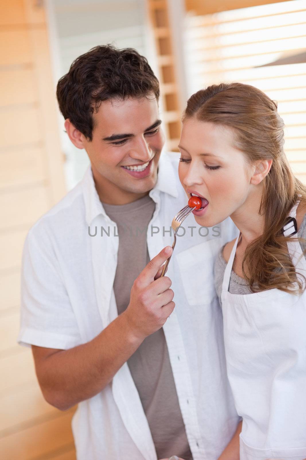 Young man feeding his girlfriend with a tomatoe