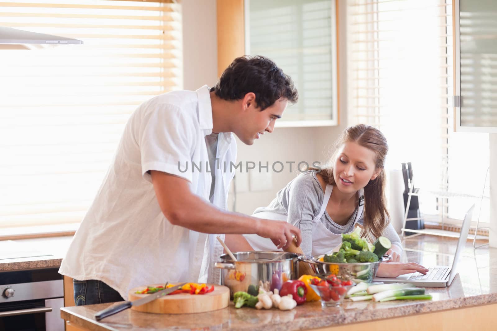 Young couple using laptop to look up recipe for their meal