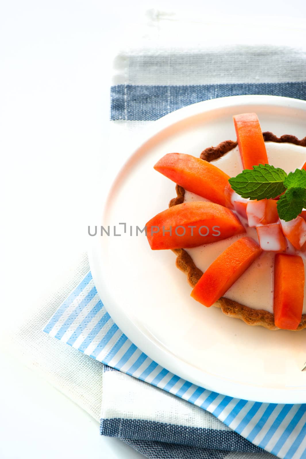 Small tarte with fresh papaya and mint as decoration on white background