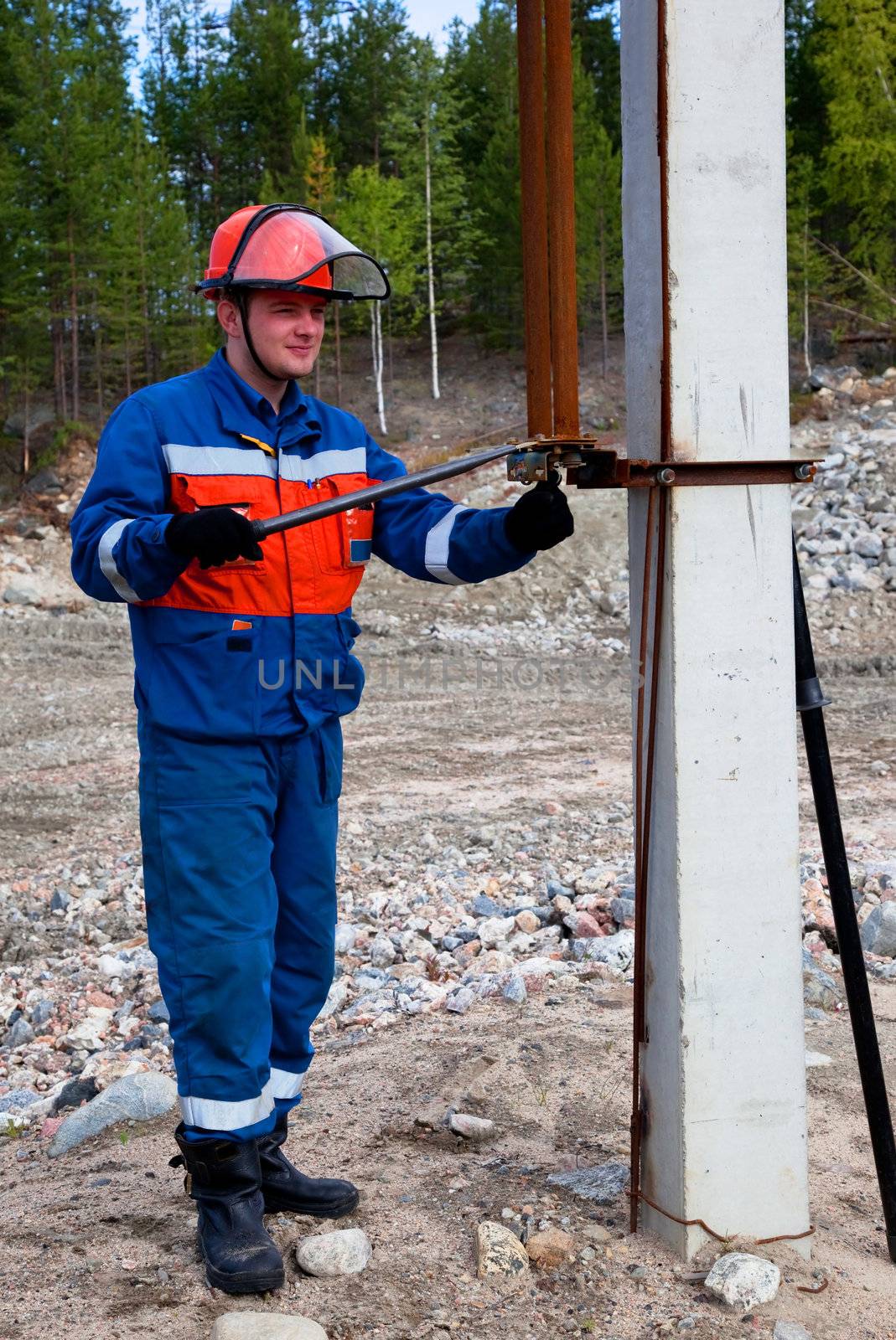 
Electrician in blue overalls makes switching. Portrait in full growth
