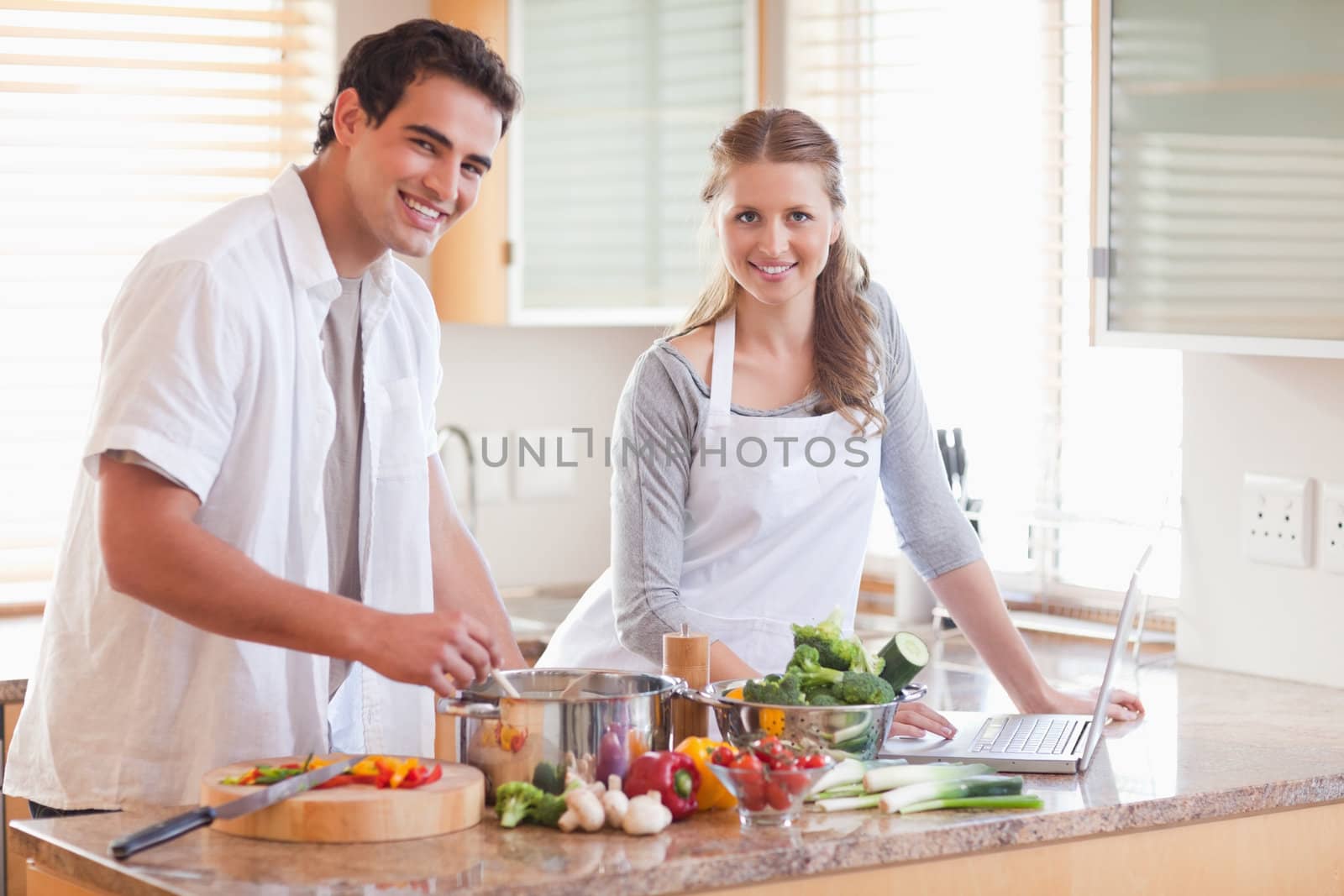 Young couple using notebook to look up recipe
