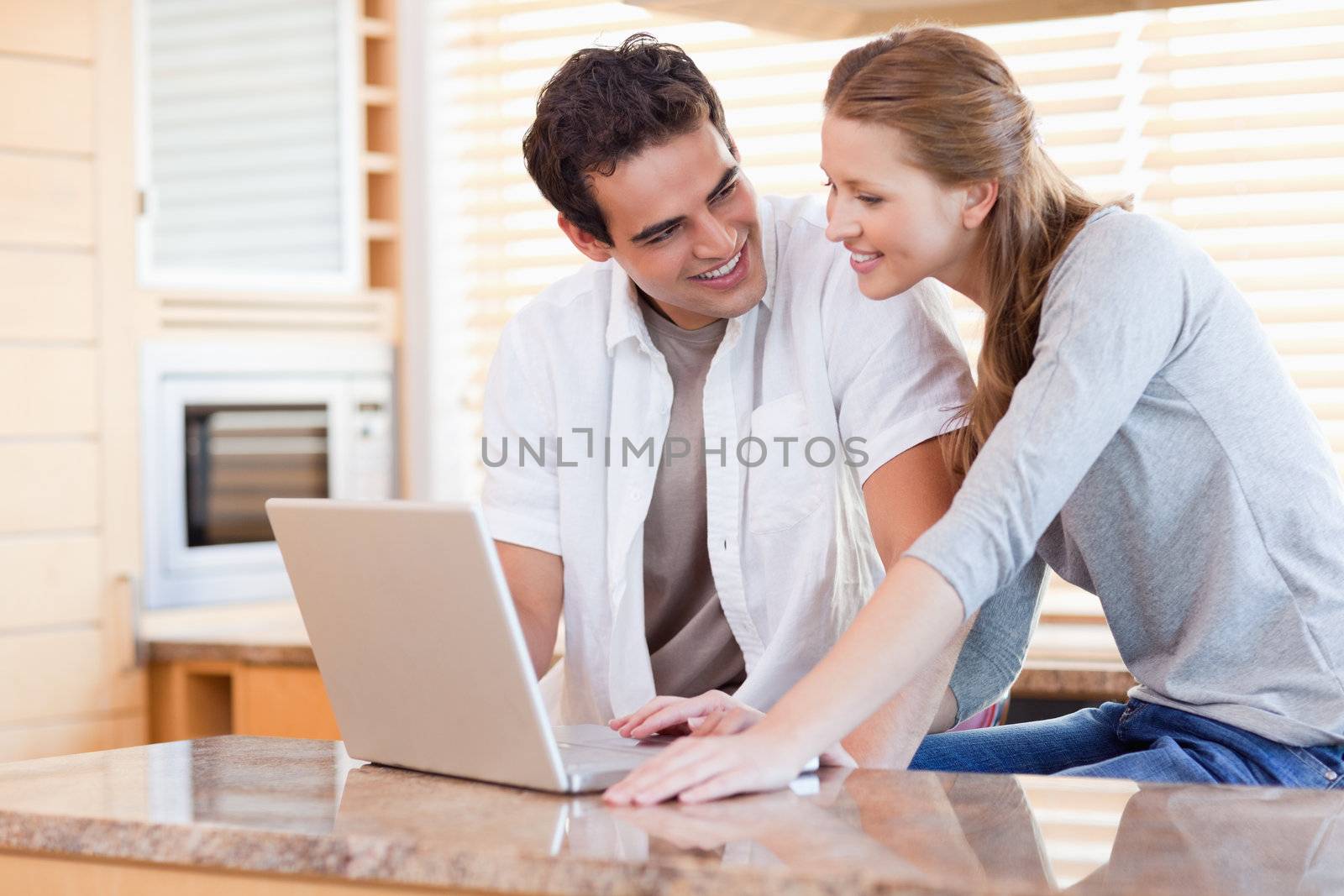 Young couple with laptop in the kitchen