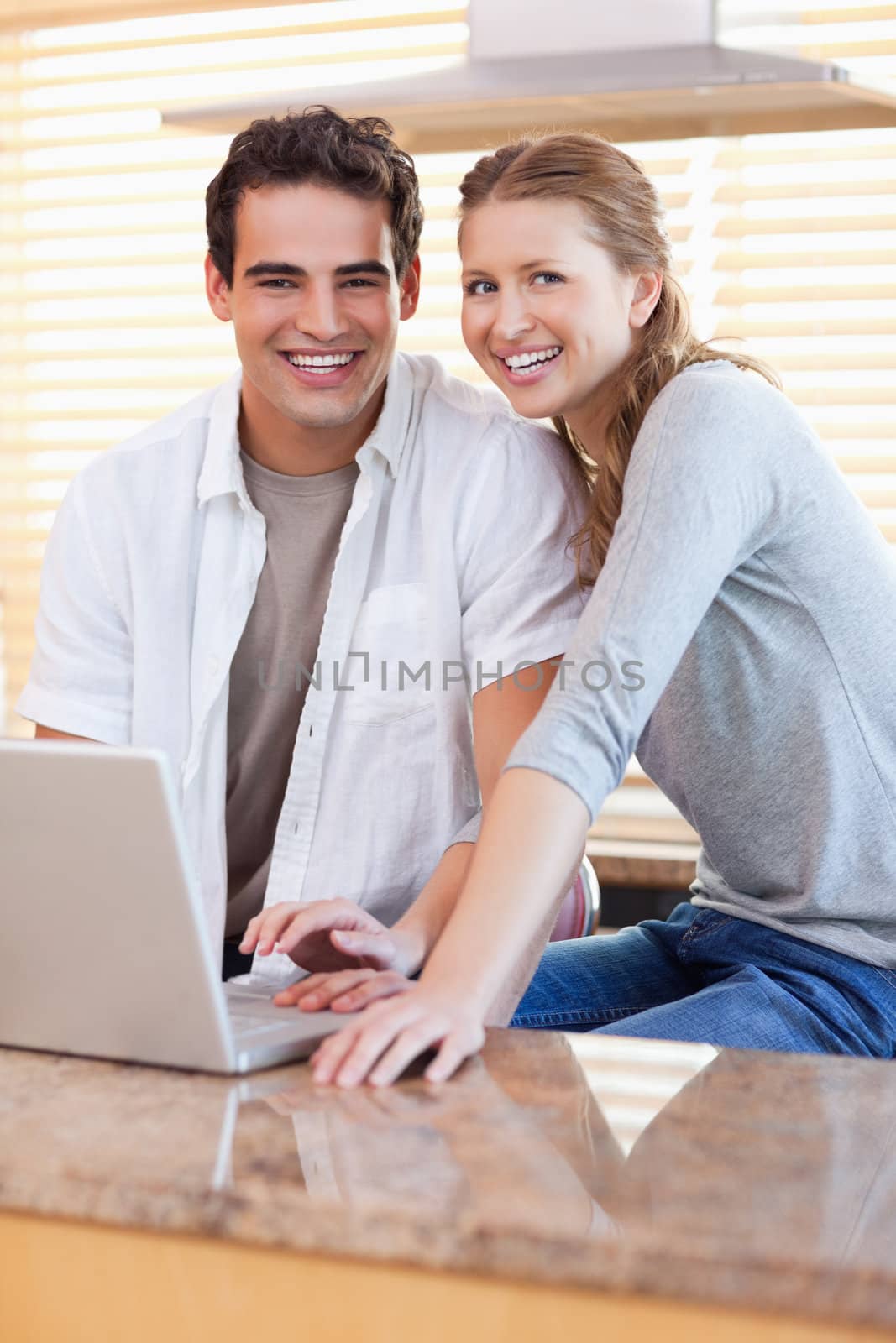 Smiling young couple with notebook in the kitchen