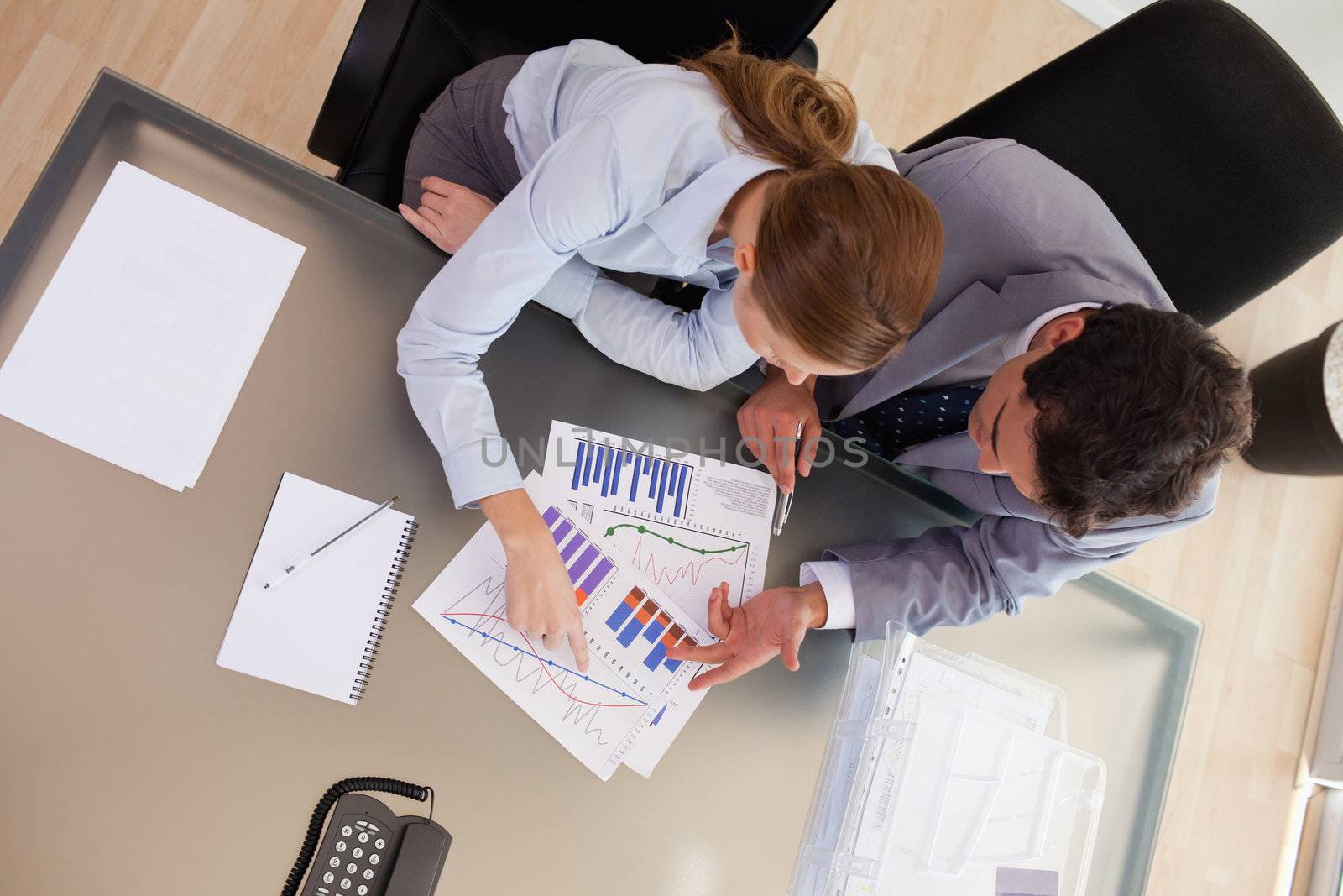 Above view of young consultant analyzing statistics with her client