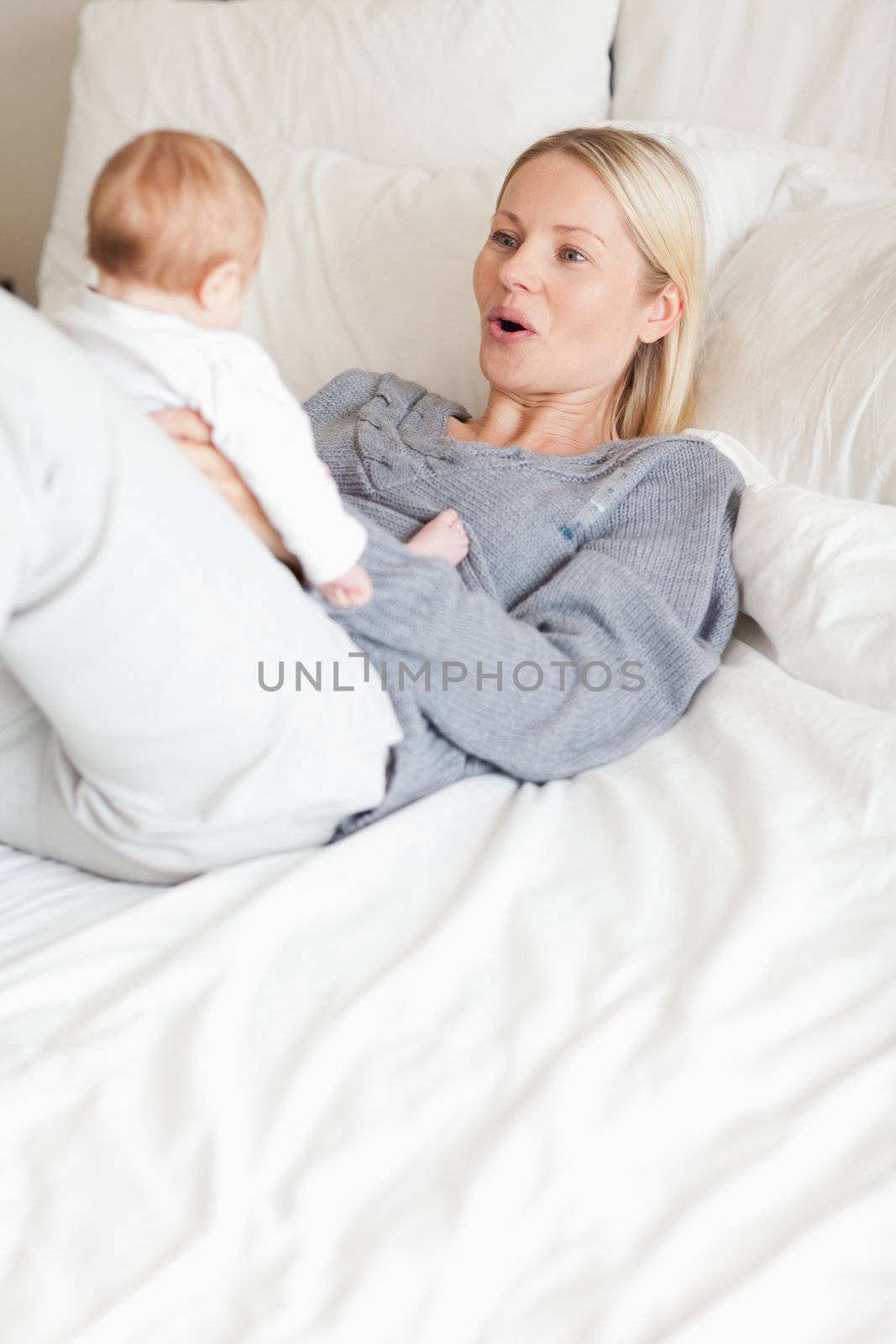 Mother playing with her baby in the bed