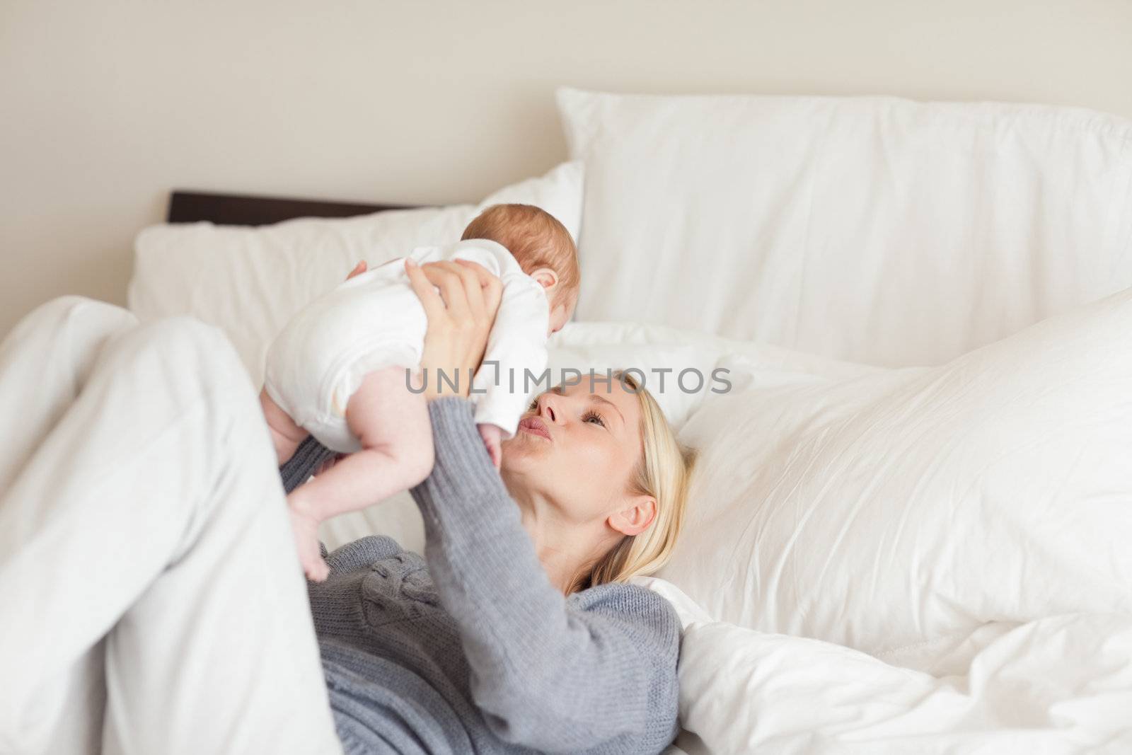 Young mother playing with her newborn in the bedroom