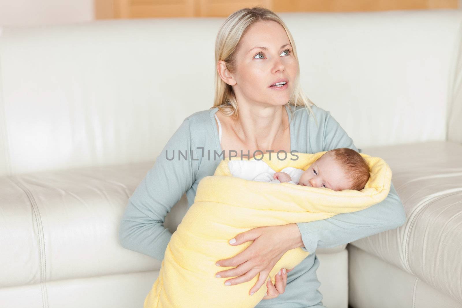 Young mother sitting with her baby in front of the couch