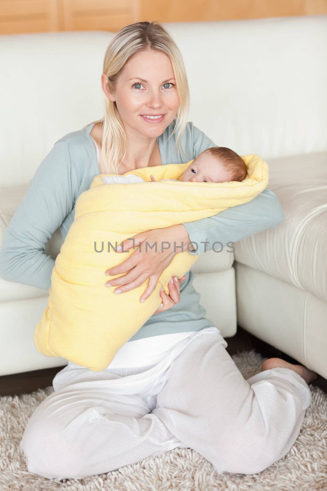 Young mother holding her baby that is wrapped into a cover
