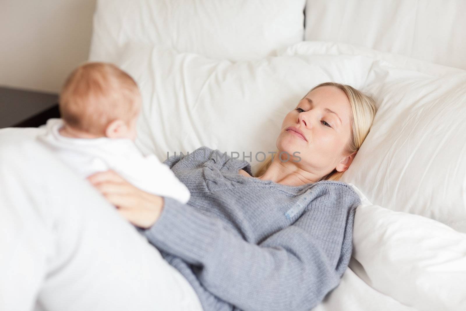 Young mother lying in the bed with her baby