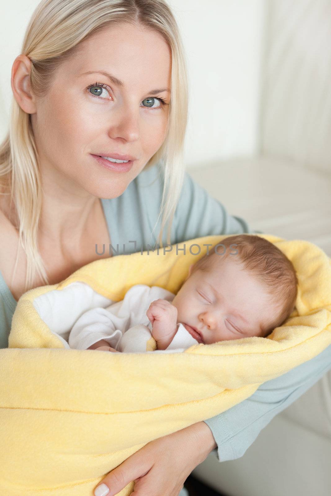 Young mom holding her sleeping baby that is wrapped up in a cover