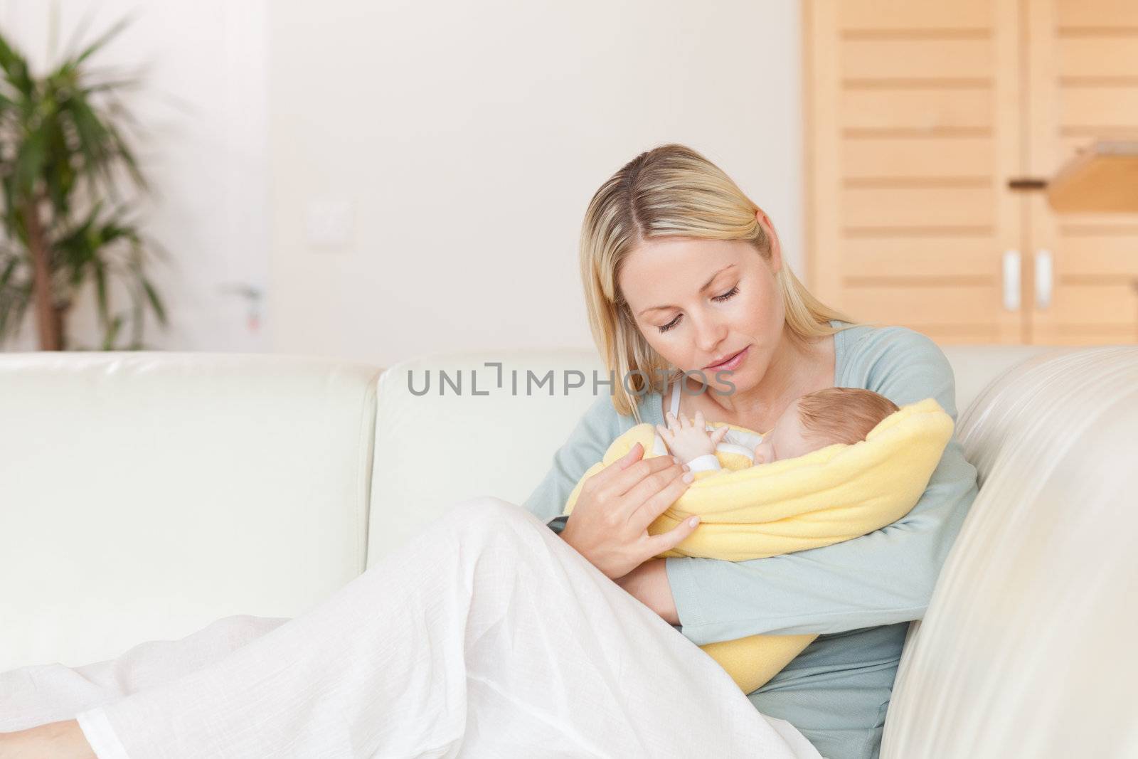 Young mother sitting on the couch with her baby in her arms