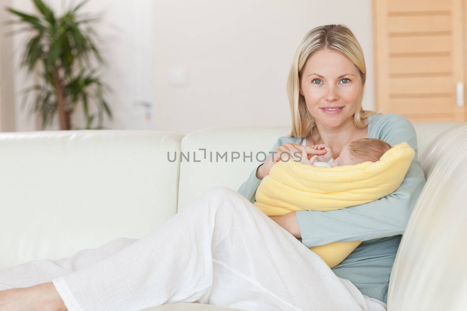 Young mother sitting on the couch holding her baby in her arms
