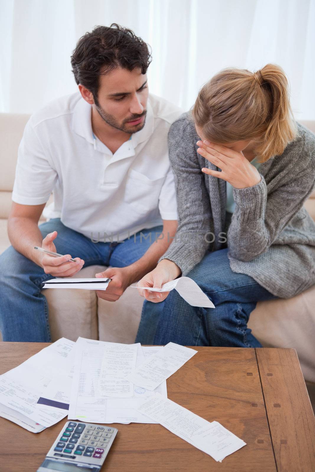 Portrait of a sad couple looking at their bills in their living room