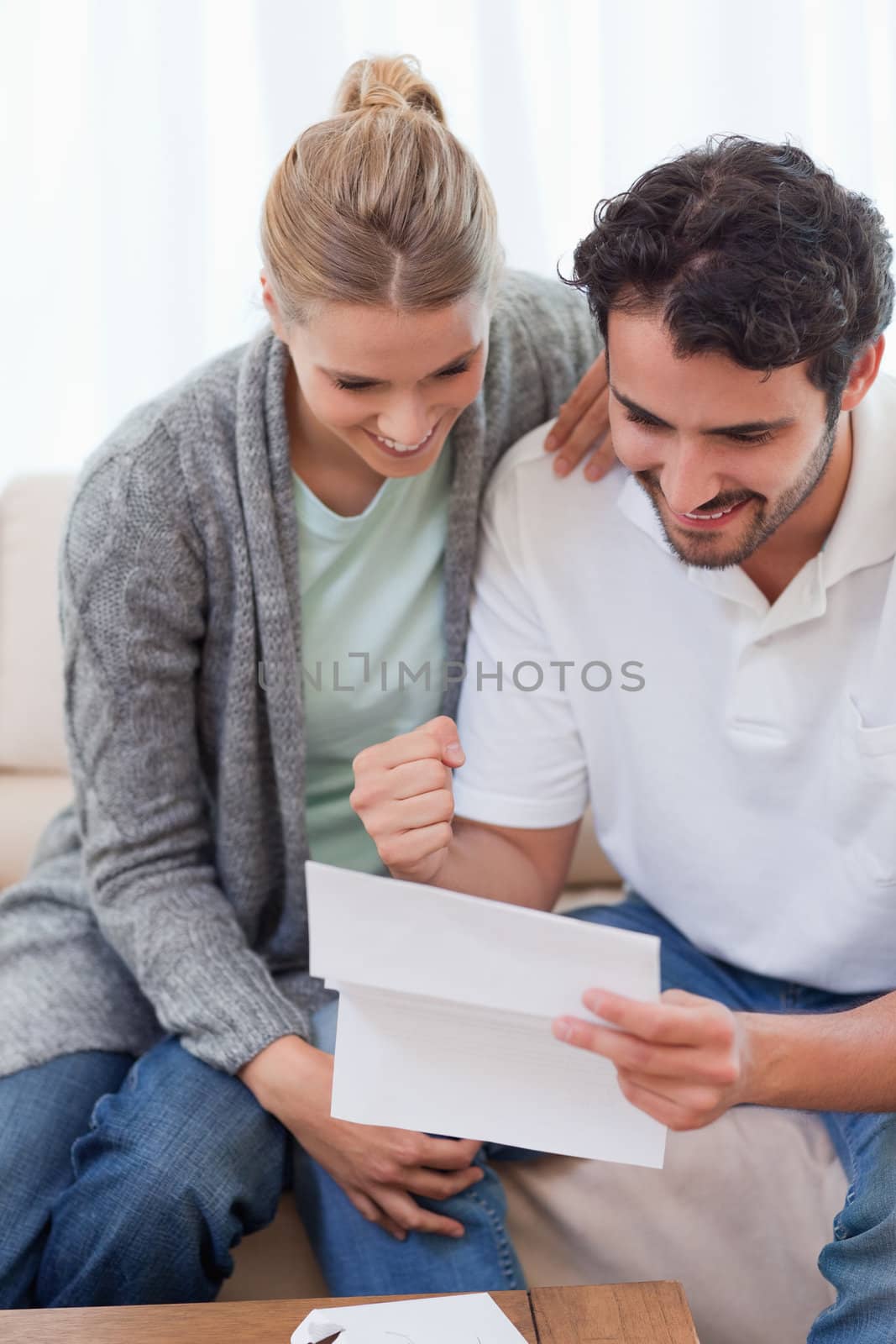 Portrait of a delighted couple reading a letter in their living room