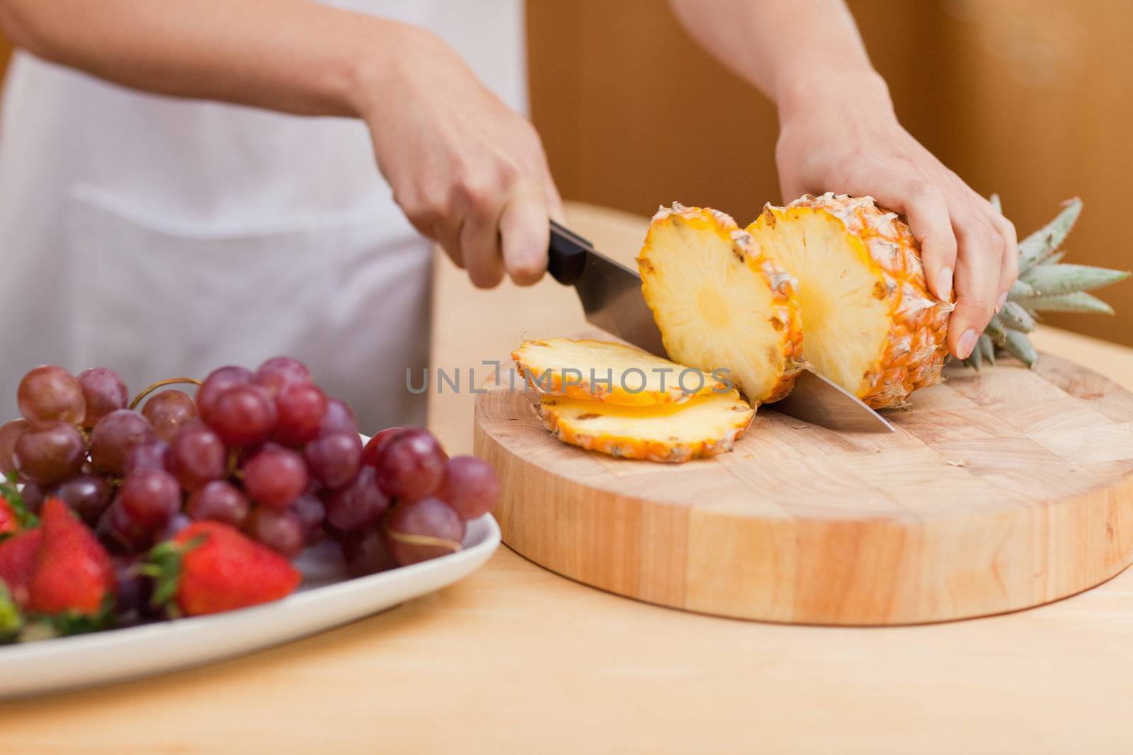 Close up of a pineapple being sliced in a kitchen