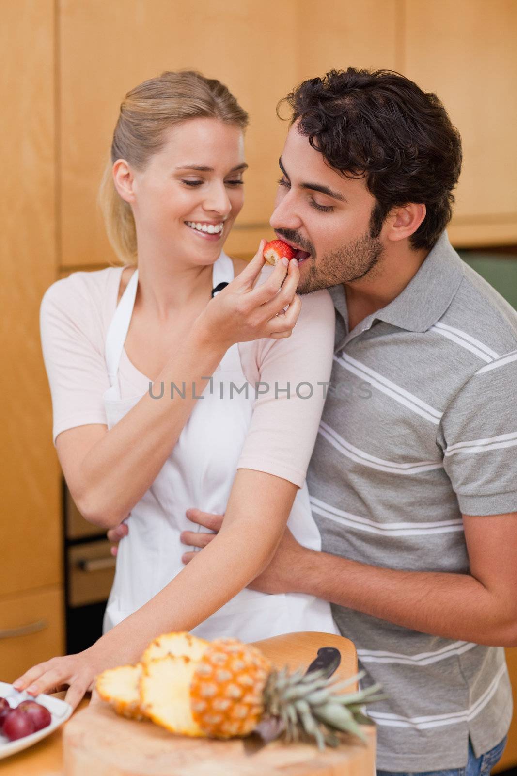 Portrait of a charming couple eating fruits in their kitchen