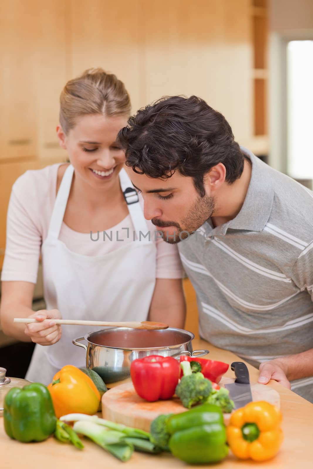 Portrait of a happy couple preparing a sauce in their kitchen