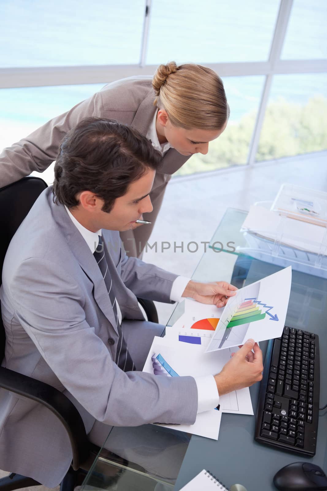 Portrait of a manager and her secretary looking at a graph in his office