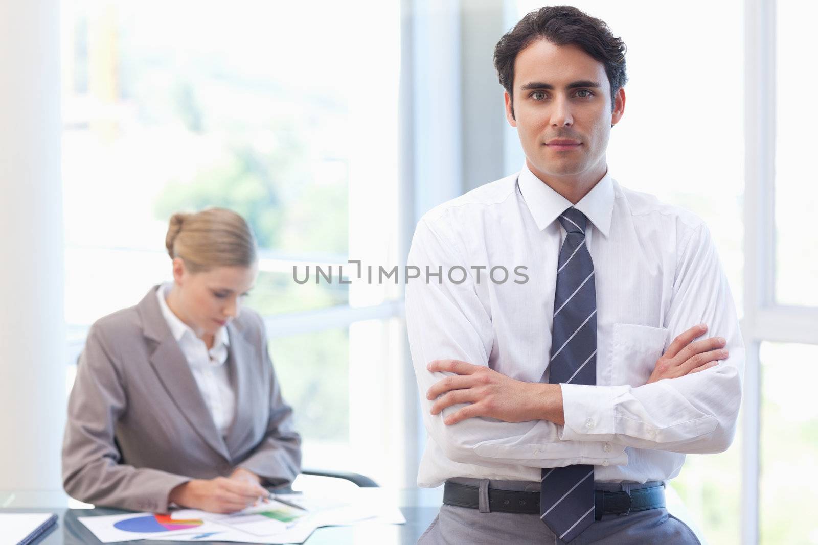 Businessman posing while his colleague is working in a meeting room