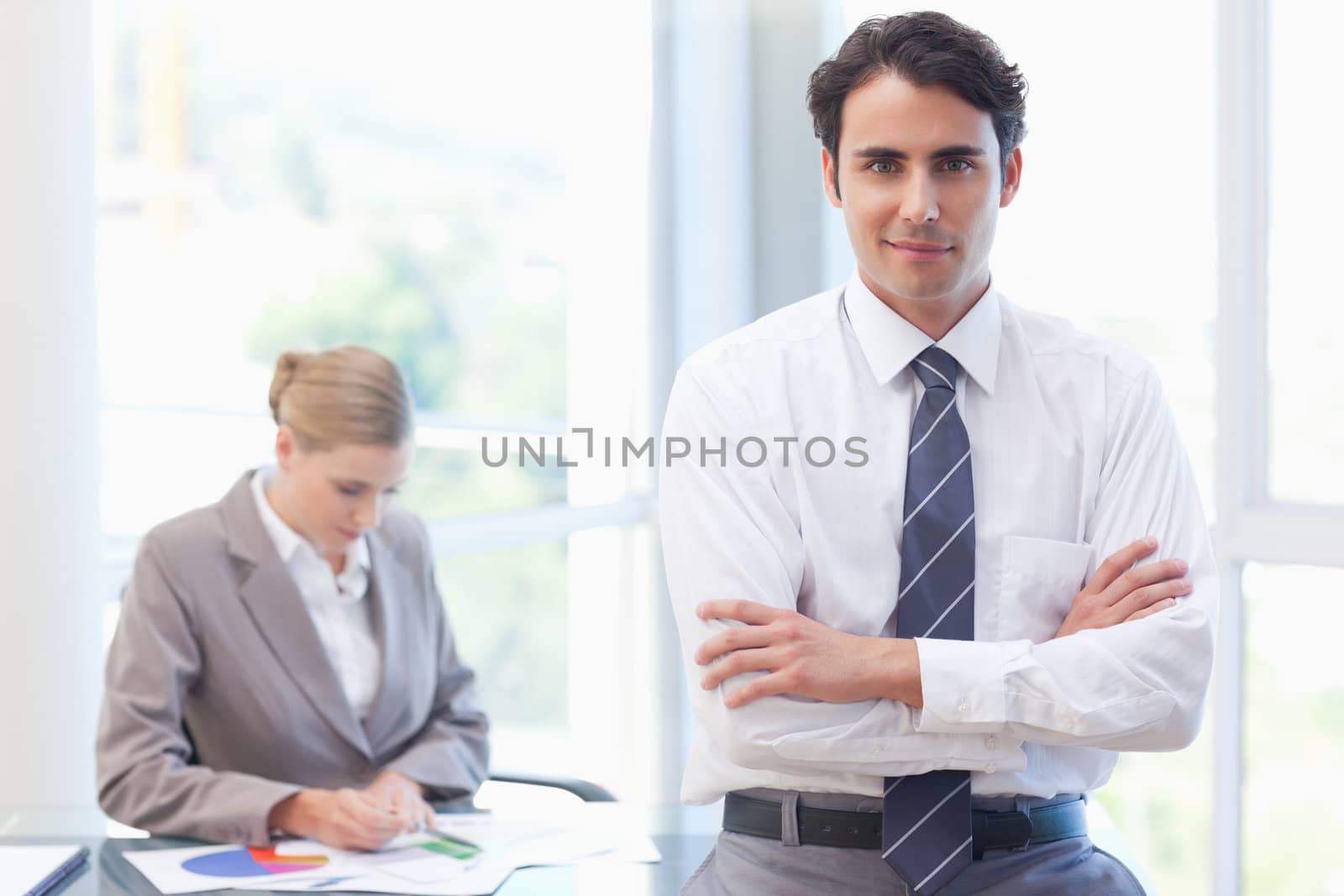 Young businessman posing while his colleague is working in a meeting room