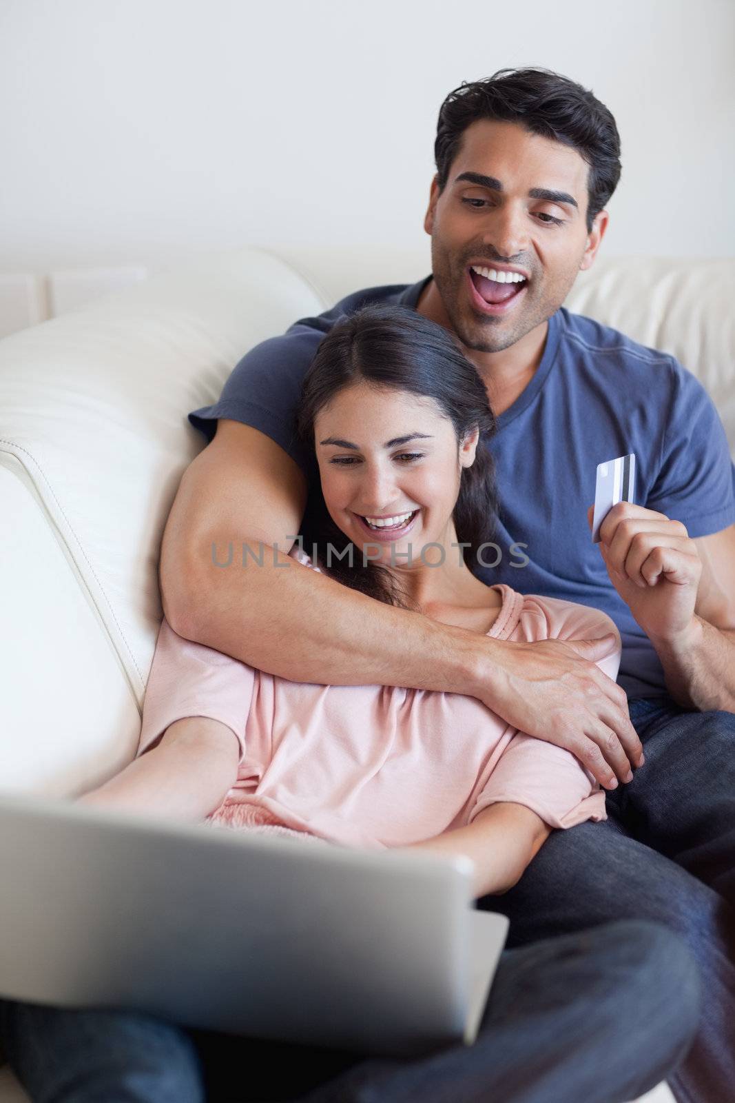 Portrait of a happy couple booking their holidays online in their living room