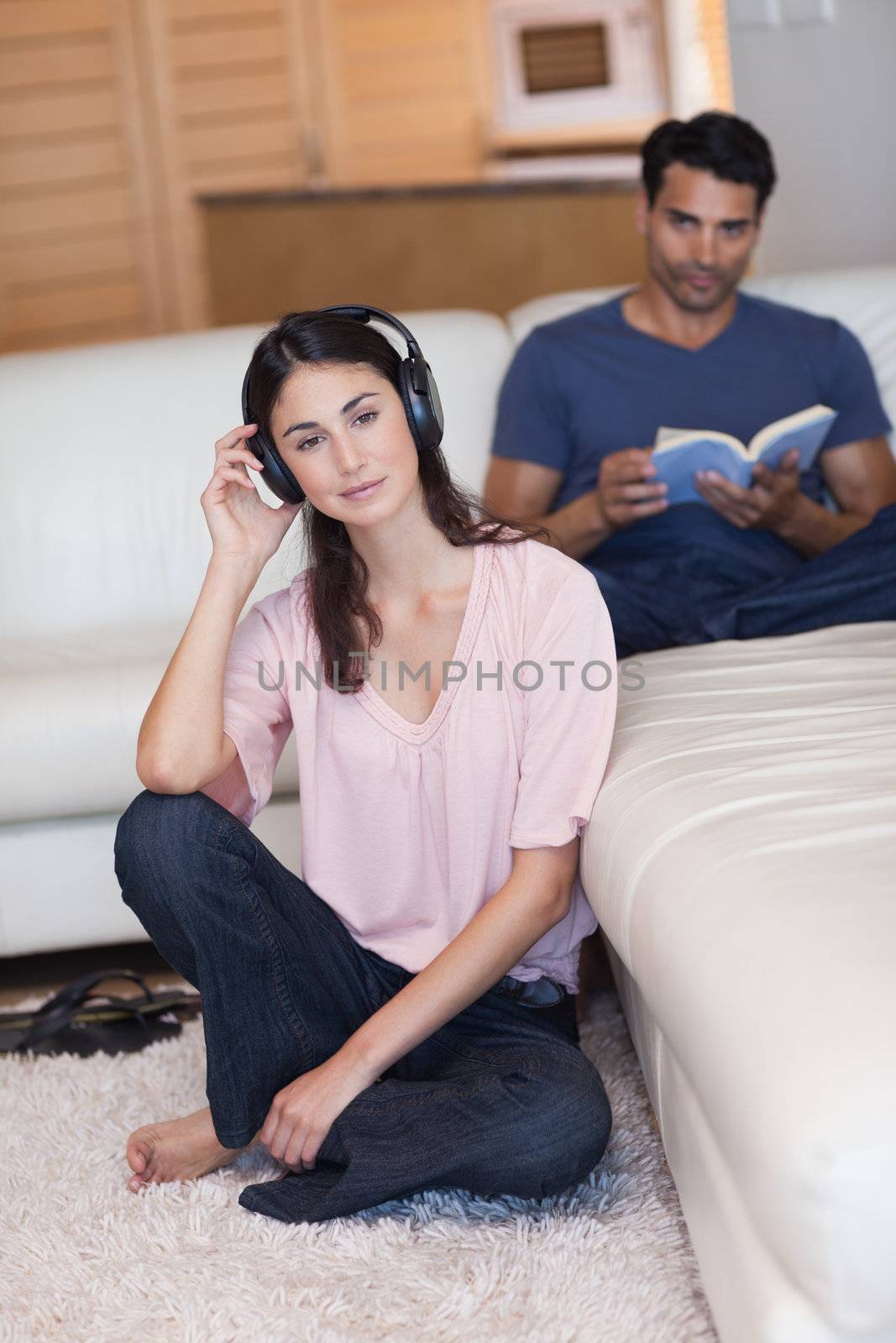 Portrait of a woman listening to music while her husband is reading a book in their living room