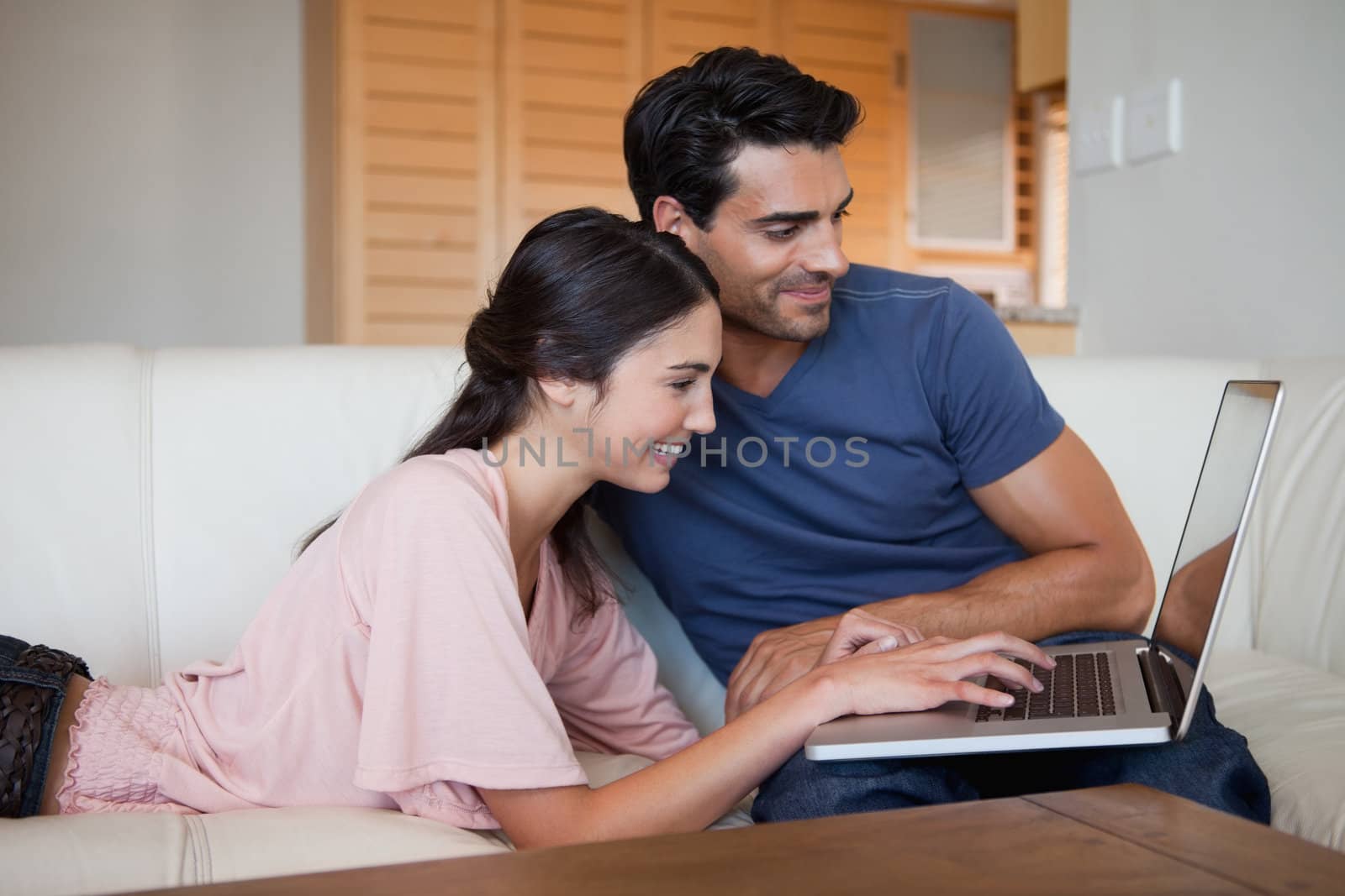 Smiling young couple using a laptop in their living room